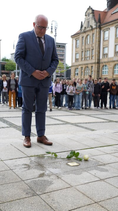 Oberbürgermeister Sven Schulze legt eine Rose auf dem frisch verlegten Stolperstein nieder