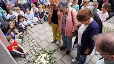 Teilnehmende der Stolpersteinverlegung legen Rosen nieder