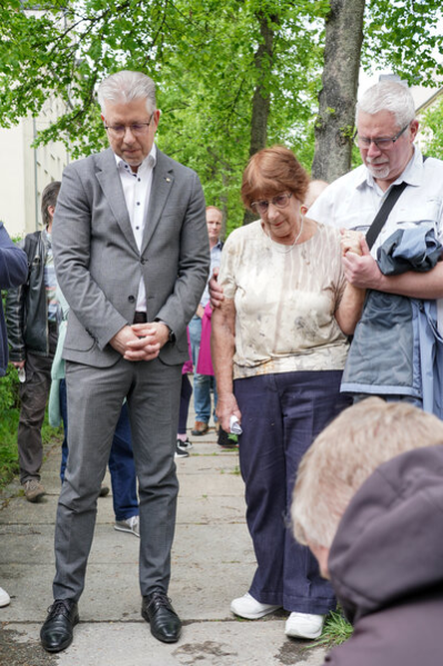 Tana Sachs und Herr Burghart blicken im Gedenken auf den Stolperstein hinab.