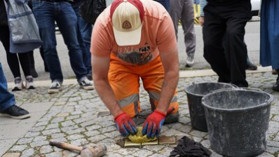 Ein Mitarbeiter des Chemnitz Bauhofes verlegt die Stolpersteine für Familie Goeritz