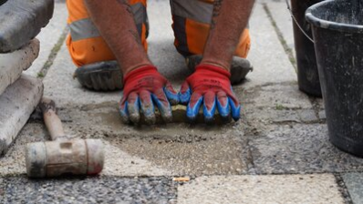 Ein Mitarbeiter des Chemnitzer Bauhofes verlegt die Stolpersteine für Familie Rappel