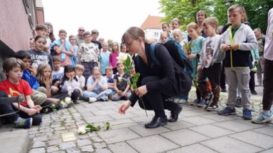 Teilnehmende der Stolpersteinverlegung legen Rosen nieder
