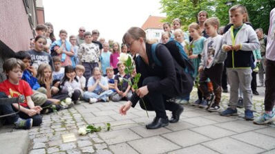 Teilnehmende der Stolpersteinverlegung legen Rosen nieder