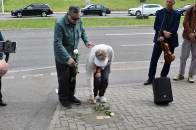 Sonia Ascher und ihr Mann legen Rosen an den Stolperstein nieder.