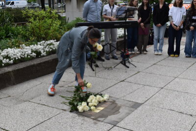 Angehörige legen Rosen am Stolperstein nieder.