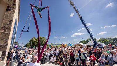 Junge Akrobatin hängt an einem Tuch in der Luft im Sportforum Chemnitz, im Hintergrund ist das Publikum zu sehen.