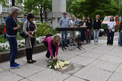 Angehörige legen Rosen am Stolperstein nieder.