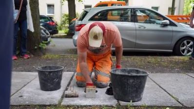 Ein Mitarbeiter des Chemnitzer Bauhofes verlegt den Stolperstein für Johannes Strauch