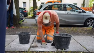 Ein Mitarbeiter des Chemnitzer Bauhofes verlegt den Stolperstein für Johannes Strauch