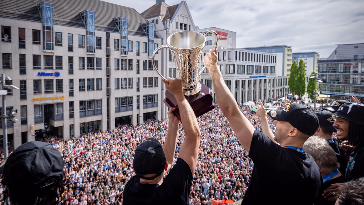 Historischer Triumph: Die Basketballer der Niners Chemnitz gewannen im April den Europapokal und präsentierten ihn auf dem Rathausbalkon, bejubelt von tausenden Fans auf dem Markt. Zuvor trugen sie sich ins Goldene Buch der Stadt ein.