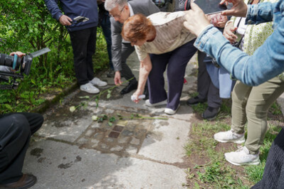 Herr Burghart und Tana Sachs legen Rosen am Stolperstein ab.