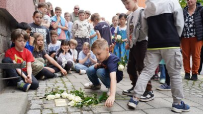 Teilnehmende der Stolpersteinverlegung legen Rosen nieder