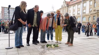 Teilnehmende an der Stolpersteinverlegung legen Blumen nieder