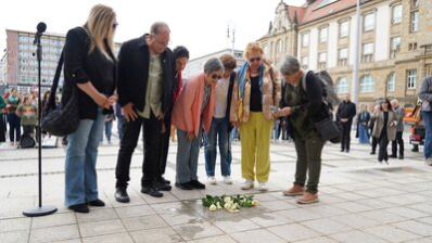 Teilnehmende an der Stolpersteinverlegung legen Blumen nieder
