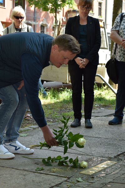Pate, Thomas Wabst, legt eine Rose neben die Stolpersteine.