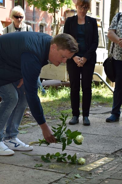 Pate, Thomas Wabst, legt eine Rose neben die Stolpersteine.