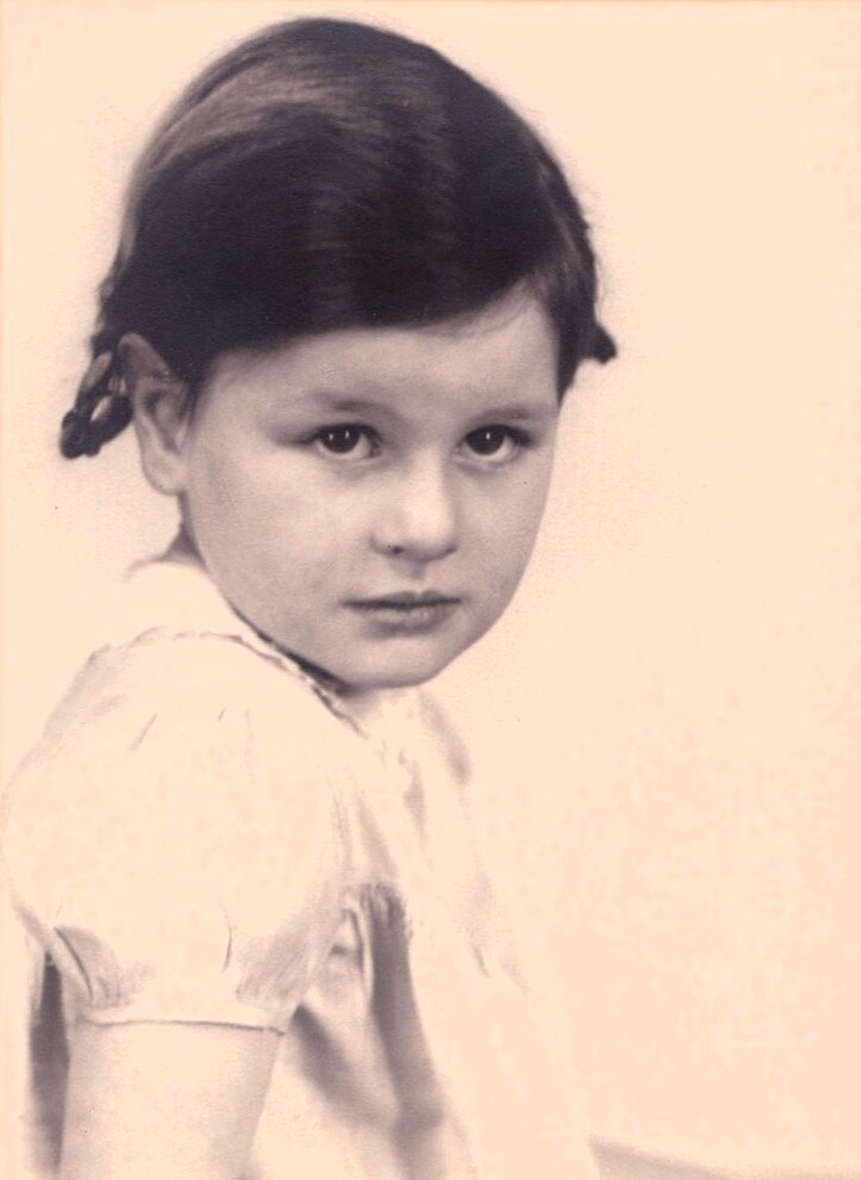Auf einem Schwarz-Weiß-Foto ist Tochter Margarete Firnbacher zu sehen. Sie trägt ihre Haare in hochgesteckten, geflochtenen Zöpfen und blickt unbegeistert in die Kamera. Sie ist etwa 4 Jahre alt.