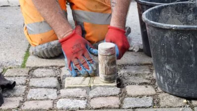 Ein Mitarbeiter des Chemnitzer Bauhofs verlegt die Stolpersteine für Familie Hoff