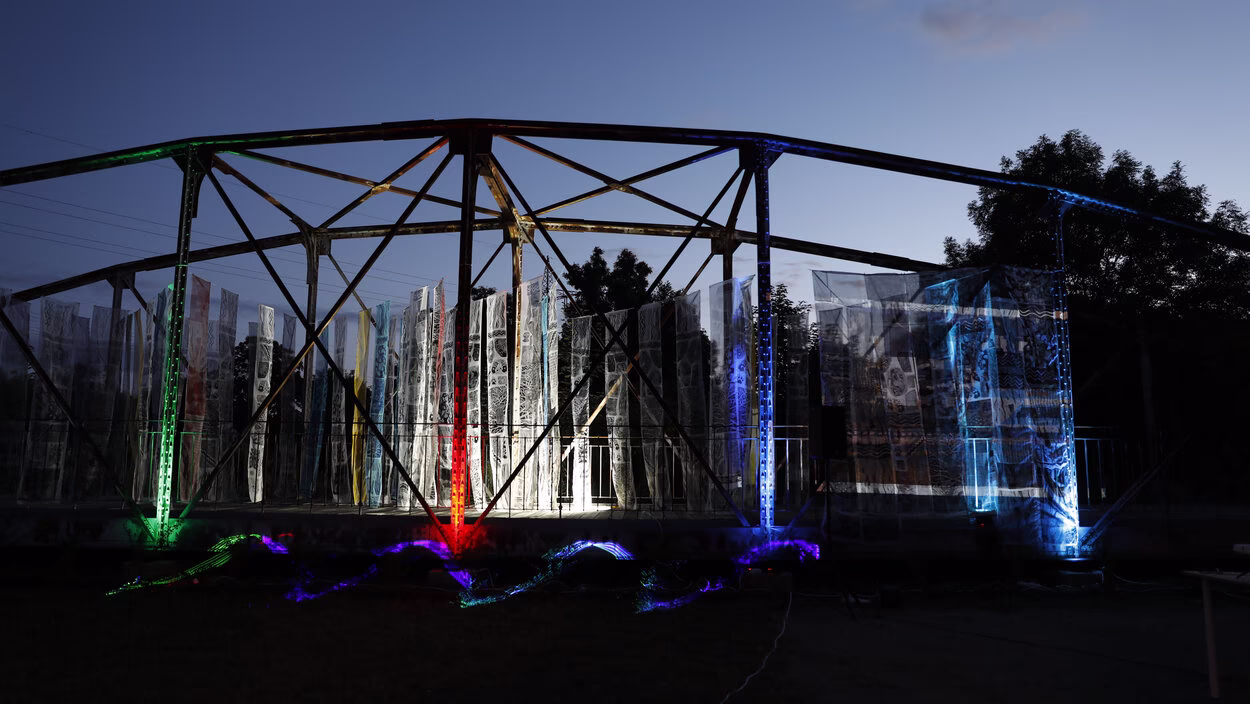 Historische Fischwegbrücke in Chemnitz nachts, beleuchtet, mit bunten Stoffbahnen im Rahmen einer Kunstaktion.