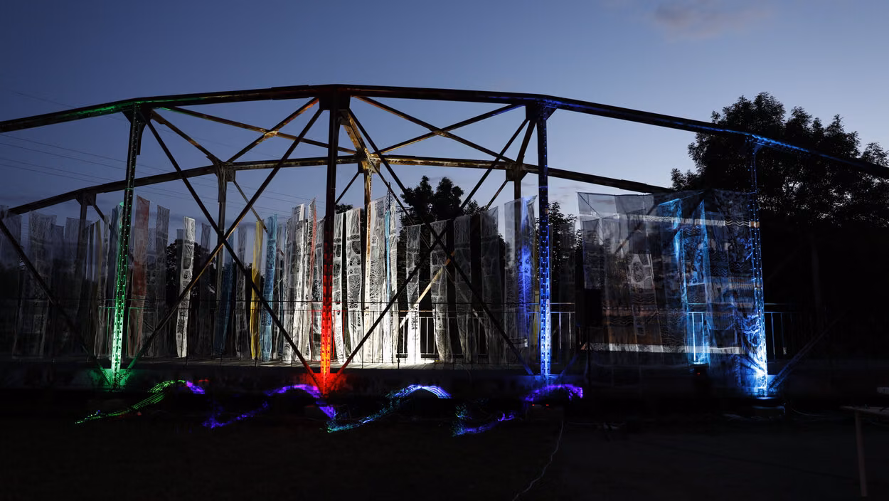 Historische Fischwegbrücke in Chemnitz nachts, beleuchtet, mit bunten Stoffbahnen im Rahmen einer Kunstaktion.