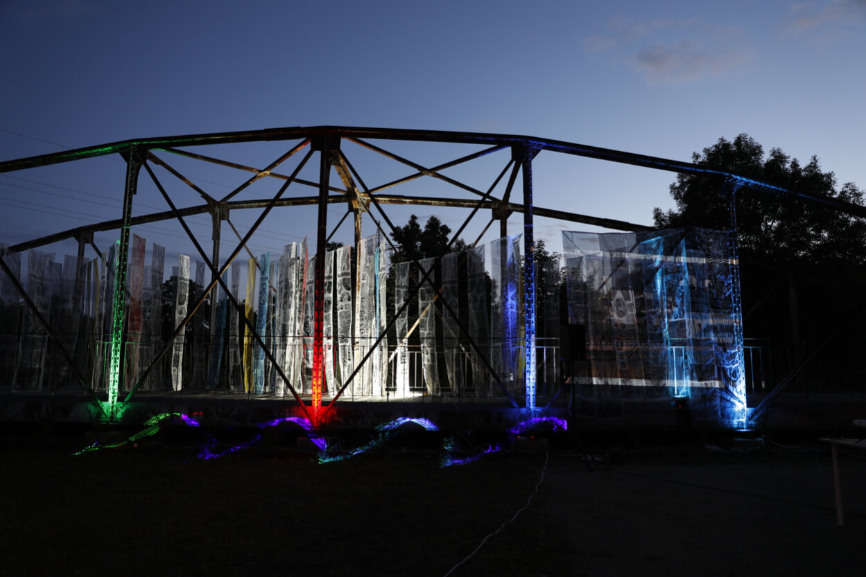 Historische Fischwegbrücke in Chemnitz nachts, beleuchtet, mit bunten Stoffbahnen im Rahmen einer Kunstaktion.