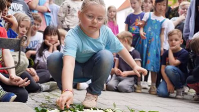Teilnehmende der Stolpersteinverlegung legen Rosen nieder