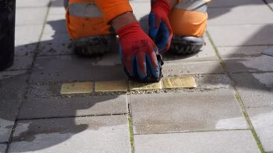 Ein Mitarbeiter des Chemnitz Bauhofs verlegt die Stolpersteine für Familie Bulka