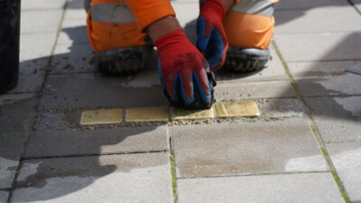 Ein Mitarbeiter des Chemnitz Bauhofs verlegt die Stolpersteine für Familie Bulka