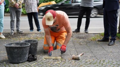 Ein Mitarbeiter des Bauhofs der Stadt Chemnitz verlegt die Stolpersteine für Familie Kagan