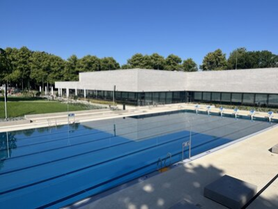 Das Bild zeigt das 50 Meter Schwimmbecken und im Hintergrund ist das gebäude des Hallenbades zu erkennen.