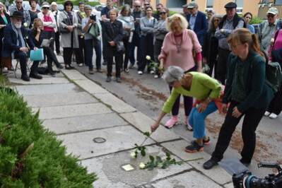 Angehörige legen Rosen am Stolperstein nieder.