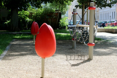 Zwei rote, tulpenförmige Sitzgelegenheiten und eine Hängematte aus Seilen als Spielgerät auf dem Lessingplatz in Chemnitz.