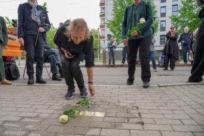 Angehörige legen Rosen an den Stolpersteinen nieder.