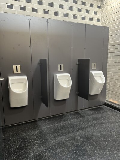 Im Bild sind 3 Pissoir abgebildet, sie sind durch Sichtschutzwände getrennt.
