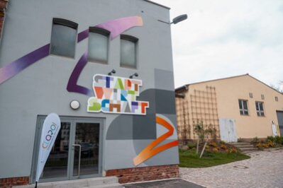 Das Bild zeigt die Stadtwirtschaft von außen. Auf dem Gebäude ist der bunte Schriftzug mit dem Namen "Stadtwirtschaft" zu sehen sowie kunstvolle Verzierungen.