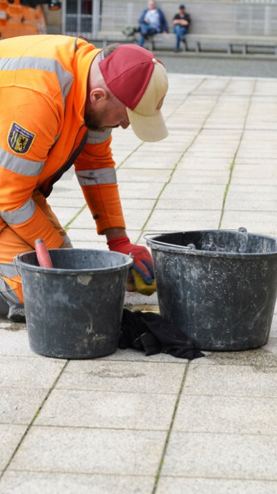 Ein Mitarbeiter des Bauhofes der Stadt Chemnitz verlegt den Stolperstein