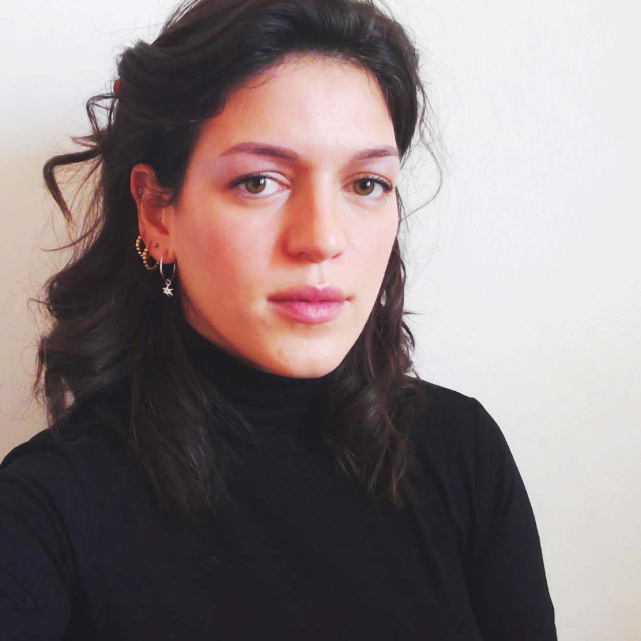 Vědkyně Roberta Ferrarini má dlouhé tmavé kudrnaté vlasy a nosí černý svetr s rolákem.