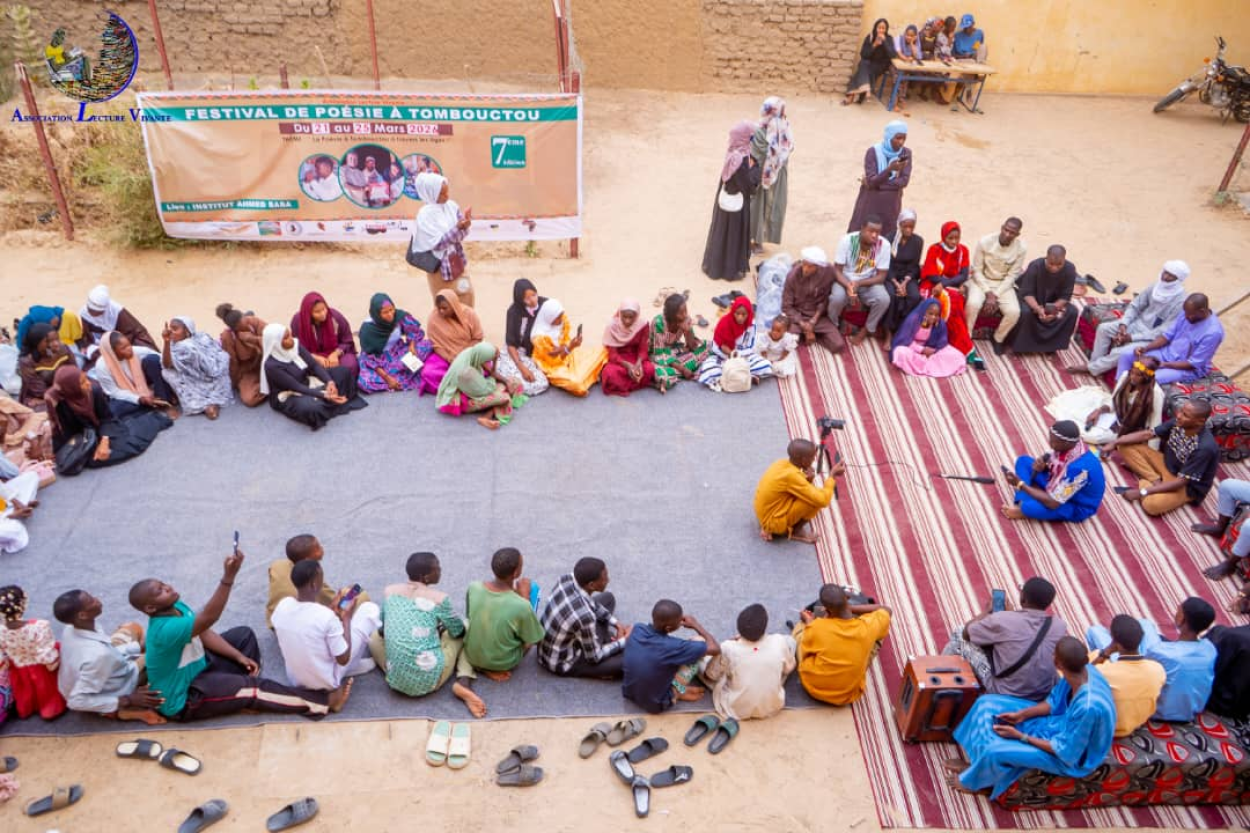Attendees at the festival in Timbuktu are sitting on the floor, listening to a reading.